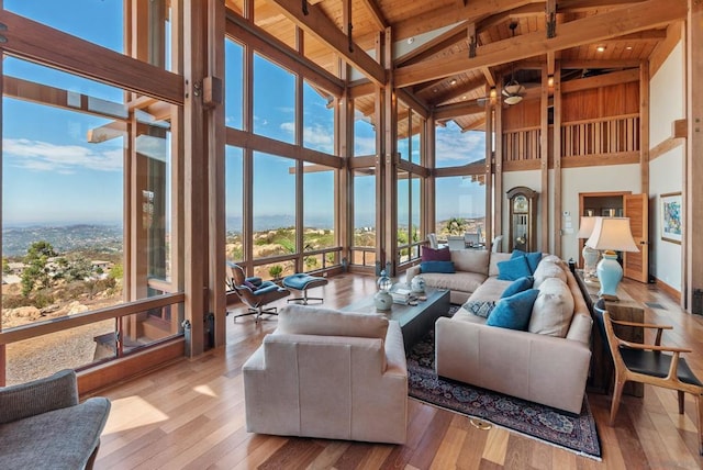 living room with beamed ceiling, high vaulted ceiling, and a wealth of natural light