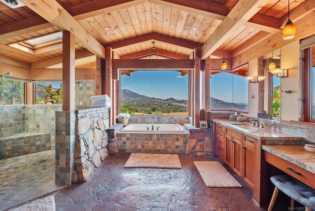 bathroom featuring a relaxing tiled tub, a mountain view, vaulted ceiling with skylight, vanity, and wood ceiling