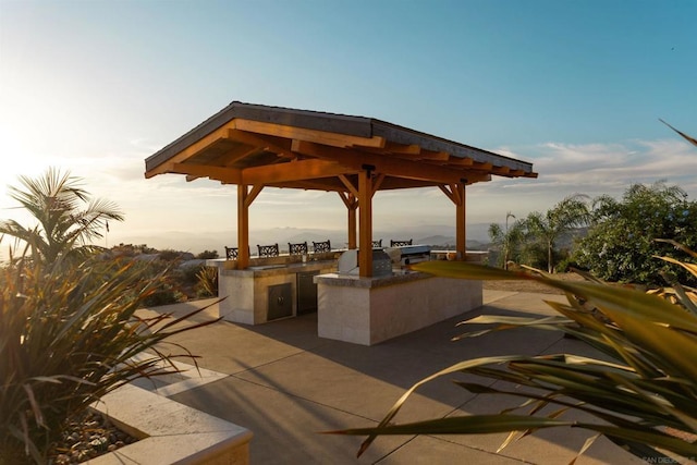 patio terrace at dusk with a gazebo and an outdoor kitchen