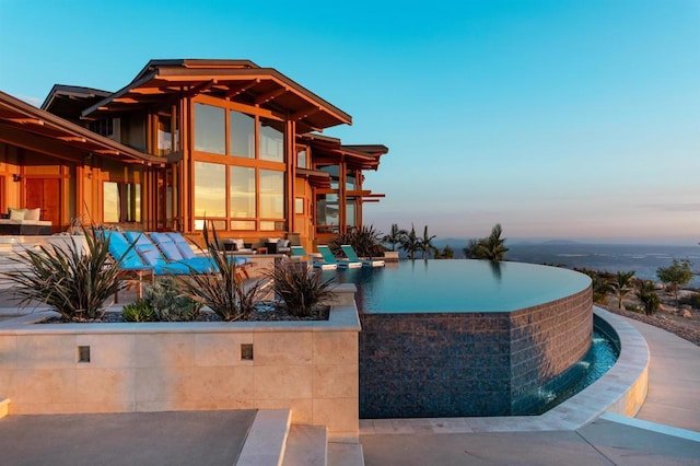 pool at dusk featuring outdoor lounge area