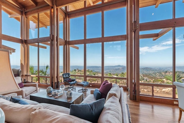 sunroom / solarium with beamed ceiling, a mountain view, a wealth of natural light, and wood ceiling