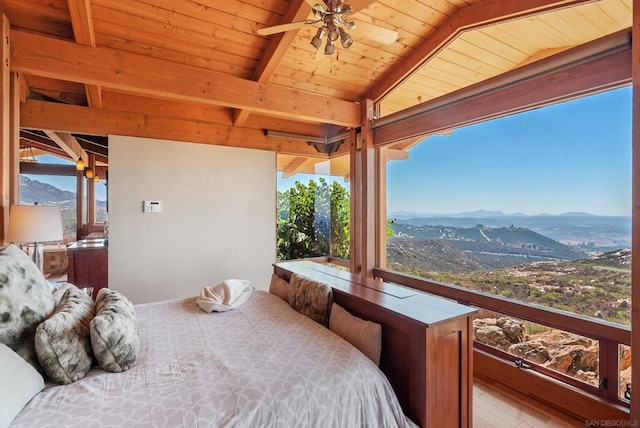 bedroom featuring a mountain view, light wood-type flooring, ceiling fan, and wooden ceiling