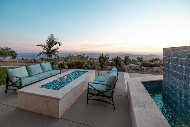 pool at dusk with a patio area and an outdoor living space with a fire pit