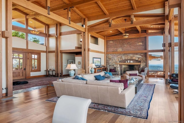 living room with a fireplace, beam ceiling, light hardwood / wood-style flooring, and wood ceiling