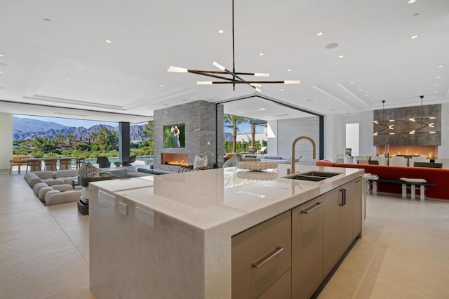 kitchen featuring an inviting chandelier, a large fireplace, a spacious island, and sink