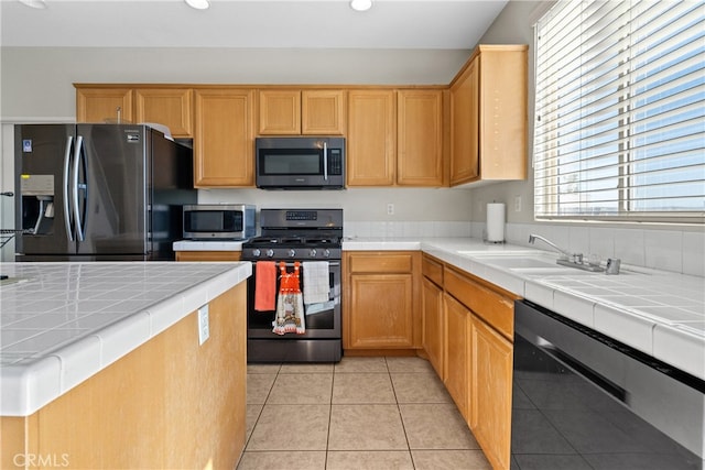 kitchen featuring light tile patterned floors, sink, stainless steel appliances, and tile countertops