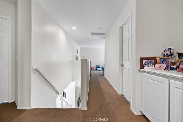 hall with dark colored carpet