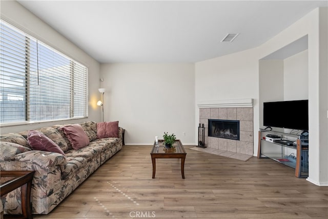 living room featuring wood-type flooring and a tile fireplace