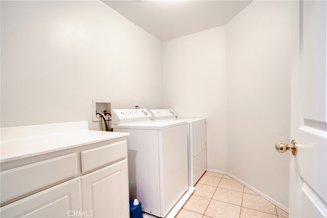 washroom featuring washing machine and clothes dryer, cabinets, and light tile patterned floors