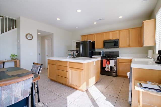 kitchen featuring light brown cabinetry, a center island, sink, black appliances, and light tile patterned floors