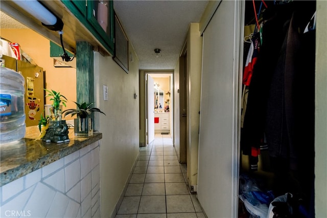 corridor featuring a textured ceiling and light tile patterned floors