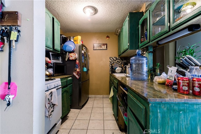 kitchen featuring green cabinetry, a textured ceiling, appliances with stainless steel finishes, and light tile patterned flooring