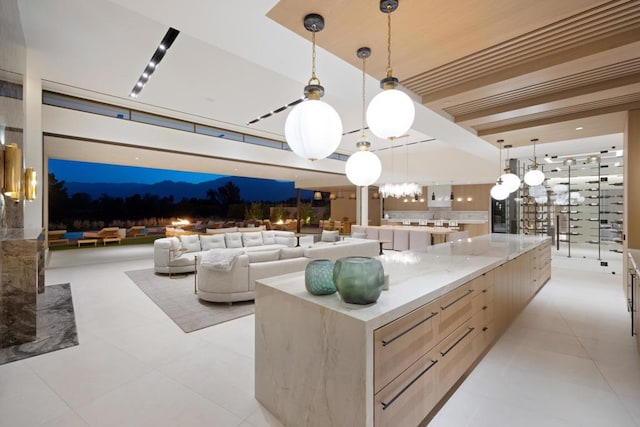 kitchen featuring light brown cabinets, light stone counters, hanging light fixtures, and a large island