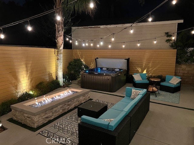 patio at night featuring an outdoor living space with a fire pit