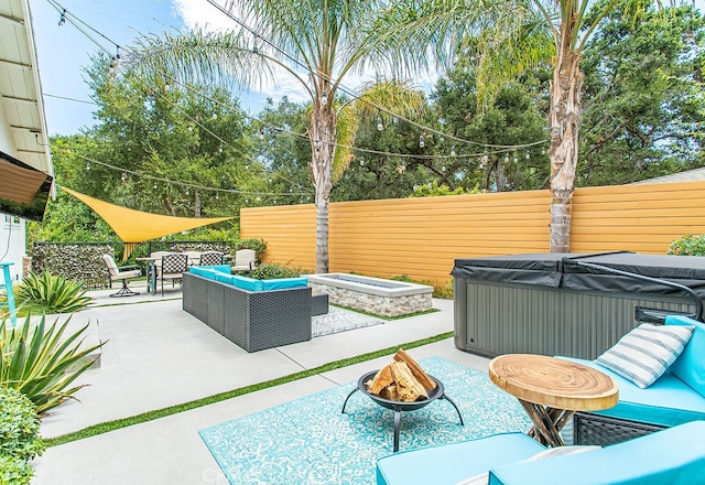 view of patio / terrace featuring a hot tub and an outdoor living space with a fire pit