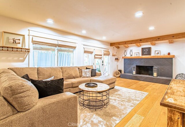 living room featuring beam ceiling, hardwood / wood-style flooring, and a fireplace