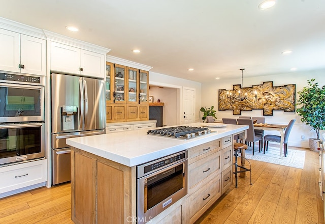 kitchen featuring a kitchen island, light hardwood / wood-style flooring, stainless steel appliances, and white cabinets