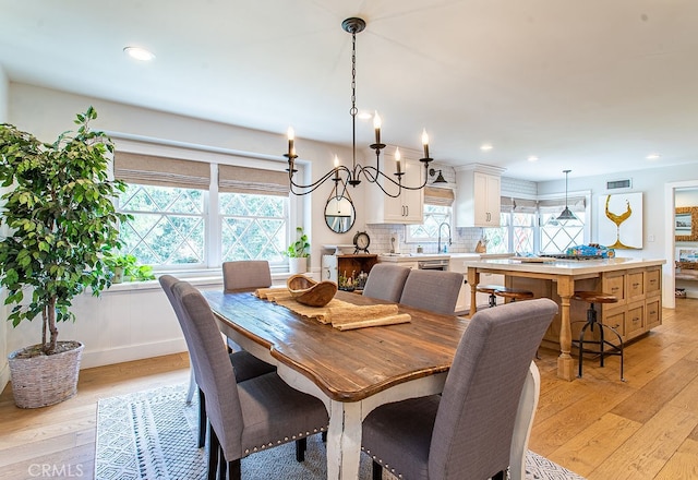 dining area with sink, light hardwood / wood-style flooring, and a chandelier