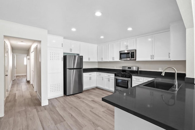 kitchen with light hardwood / wood-style floors, stainless steel appliances, sink, and white cabinets