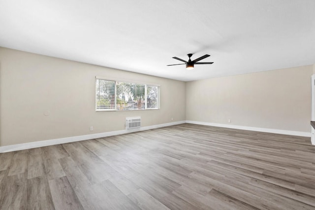 spare room featuring light hardwood / wood-style floors, ceiling fan, and a wall unit AC