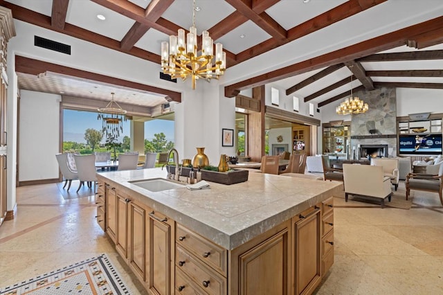 kitchen with a center island with sink, pendant lighting, an inviting chandelier, and a high end fireplace