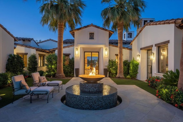 back house at dusk featuring a patio