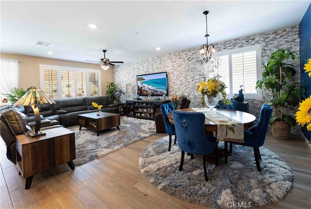 dining area featuring ceiling fan with notable chandelier, light hardwood / wood-style floors, and a healthy amount of sunlight