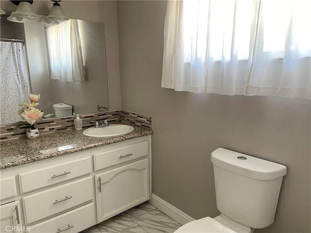 bathroom featuring toilet, marble finish floor, baseboards, and vanity