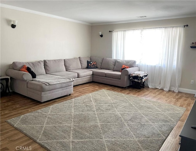 living area with visible vents, crown molding, and wood finished floors