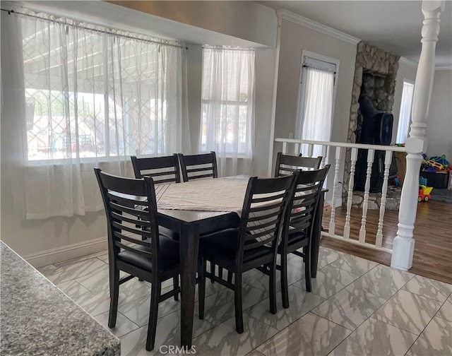 dining area with marble finish floor, ornamental molding, a wealth of natural light, and baseboards