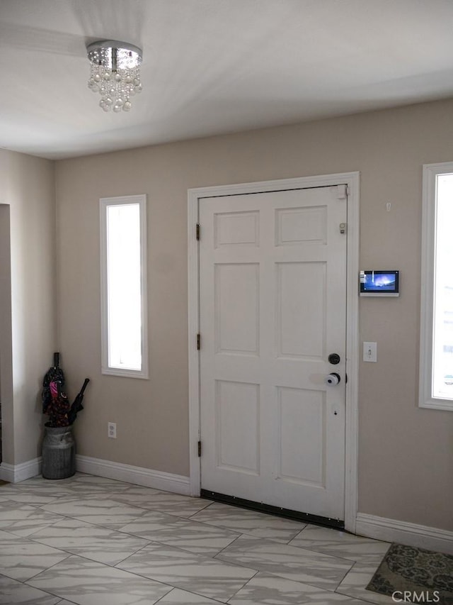 entryway featuring a chandelier and baseboards