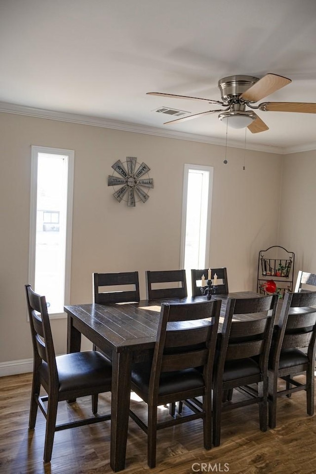 dining room with baseboards, visible vents, ornamental molding, and wood finished floors