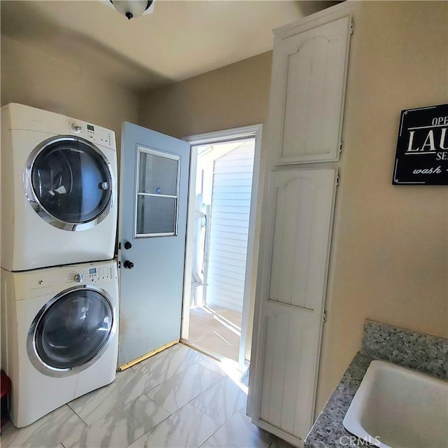 washroom featuring stacked washing maching and dryer, marble finish floor, and a sink