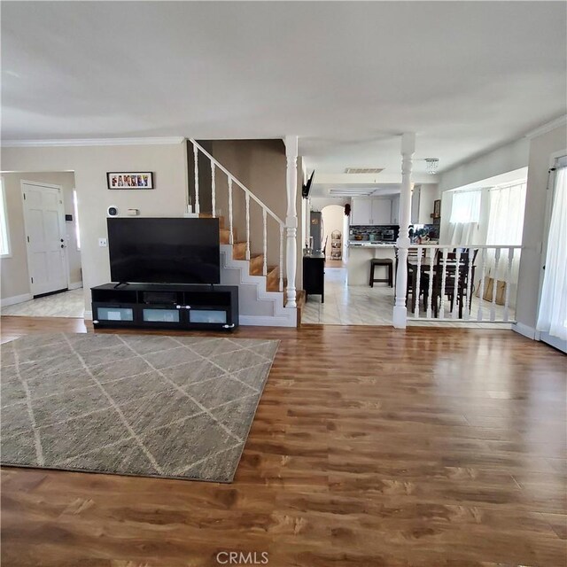 living room featuring hardwood / wood-style floors, crown molding, and decorative columns