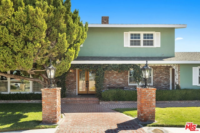 view of front of property featuring a front lawn and french doors