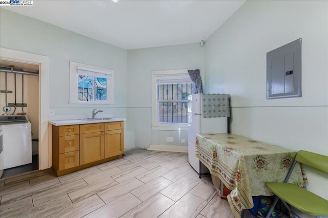 bedroom with white fridge, washer / dryer, sink, and electric panel