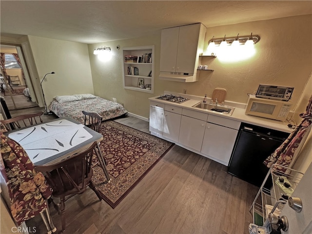 kitchen featuring dark wood-type flooring, white cabinets, a textured ceiling, stainless steel gas stovetop, and sink