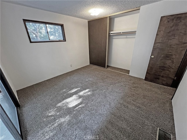 unfurnished bedroom with a textured ceiling, a closet, and carpet