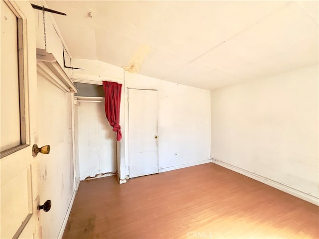 unfurnished bedroom with vaulted ceiling, a closet, and hardwood / wood-style floors