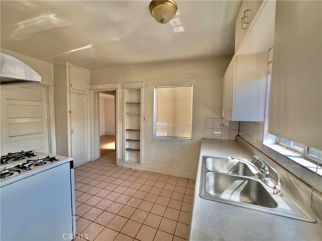 kitchen with sink, white cabinets, decorative backsplash, light tile patterned floors, and white range with gas cooktop