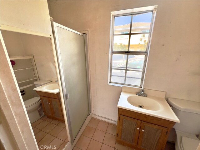 bathroom featuring tile patterned flooring, vanity, toilet, and a shower with door