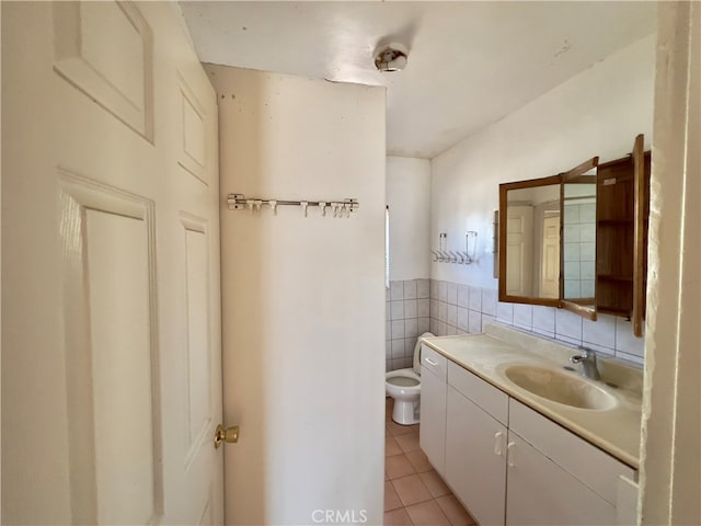 bathroom with tile walls, vanity, toilet, and tile patterned floors