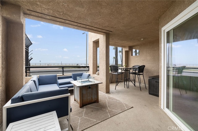 view of patio with a balcony and an outdoor living space with a fire pit