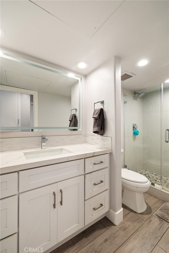 bathroom with walk in shower, vanity, hardwood / wood-style floors, and toilet