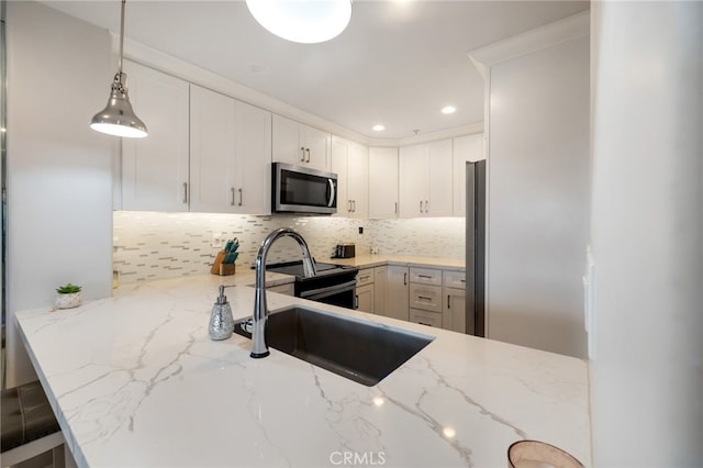 kitchen with light stone counters, decorative light fixtures, stainless steel appliances, and kitchen peninsula