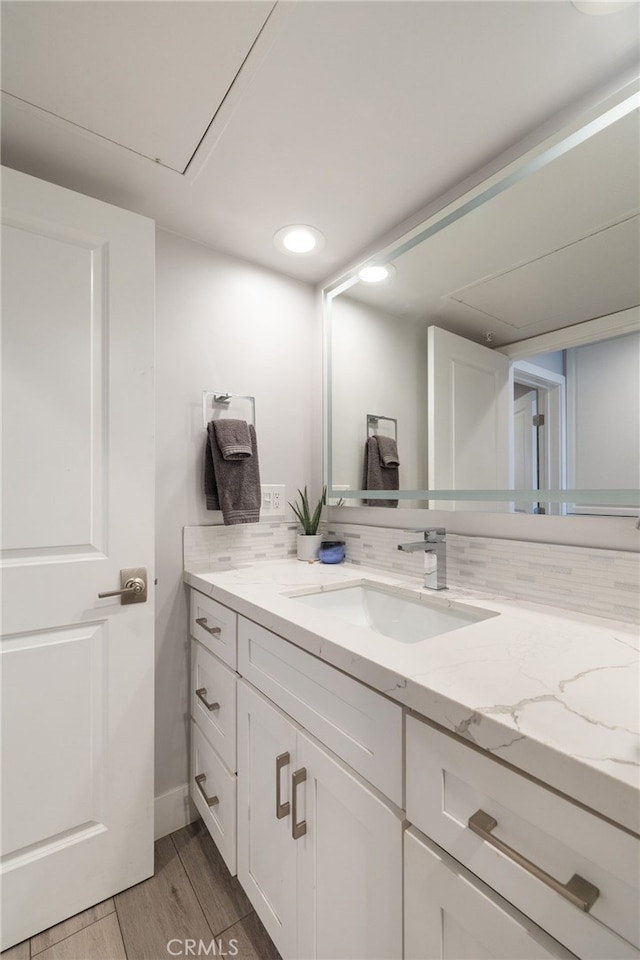 bathroom with tasteful backsplash, hardwood / wood-style floors, and vanity