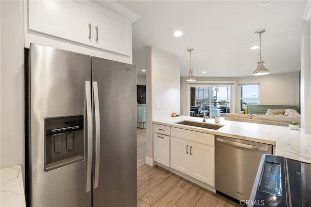 kitchen with stainless steel appliances, decorative light fixtures, light hardwood / wood-style flooring, and white cabinetry