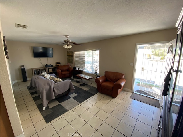 tiled living room with a wealth of natural light, ceiling fan, and a textured ceiling