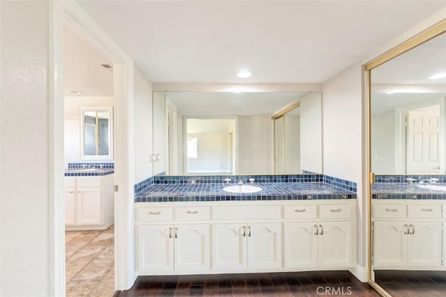 bathroom with two vanities, a sink, and wood finished floors