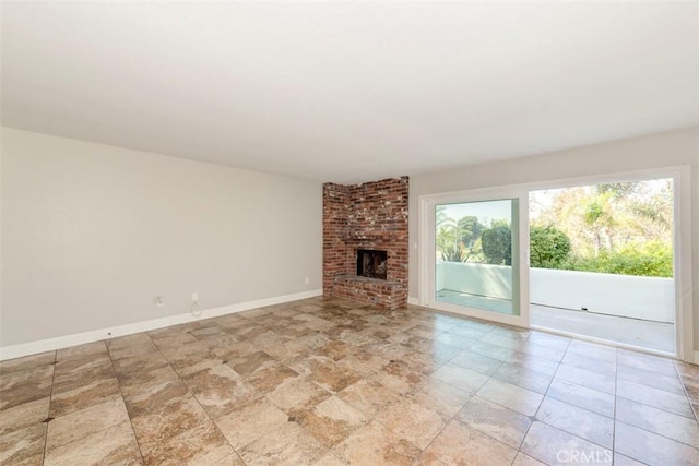 unfurnished living room with a brick fireplace and baseboards